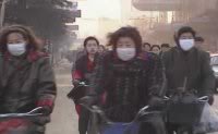 Lots of Chinese cyclists, some wearing masks against the smog